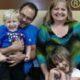 A family portrait showing a smiling Bob and Barbara Carpenter with two young children, one being held and the other resting his head on Barbara's lap.